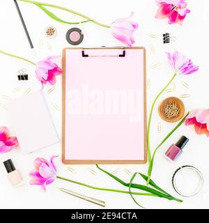Presse-papiers, carnet, stylo, fleurs de tulipe rose et cosmétiques sur fond blanc. Pose à plat Banque D'Images