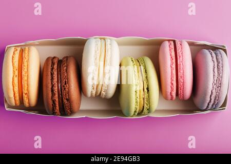 Biscuits de macarons français colorés dans un forfait sur fond rose. Gros plan, espace libre Banque D'Images