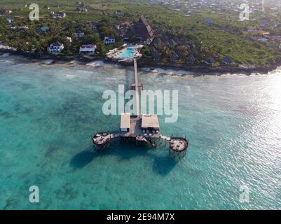 Côte nord de Zanzibar à Nungwi avec phare et toit de chaume Restaurant sur les piliers au-dessus de l'océan Banque D'Images
