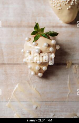 Étape par étape. De savoureuses fraises enrobées de chocolat blanc et saupoudrées de sucre sur des bakckrods en bois. saint-valentin. Banque D'Images