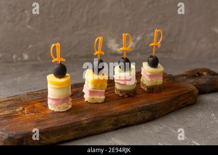 Canapés délicieux sur panneau en bois sombre. Table de buffet, mise au point sélective. Banque D'Images