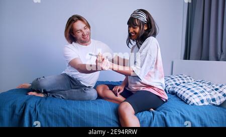 Jeune couple excité qui se serre avec un test de grossesse positif. . Photo de haute qualité Banque D'Images