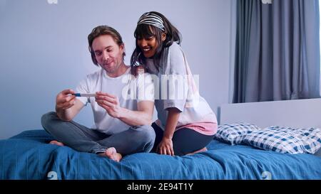 Jeune couple excité qui se serre avec un test de grossesse positif. . Photo de haute qualité Banque D'Images