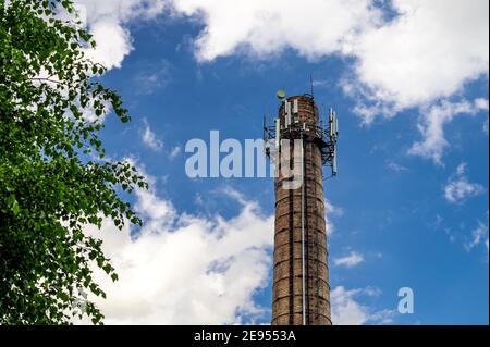 Antennes 5G sur un tuyau de brique contre un ciel nuageux. Antennes cellulaires et Internet sur le tuyau de brique de la chaufferie. Banque D'Images