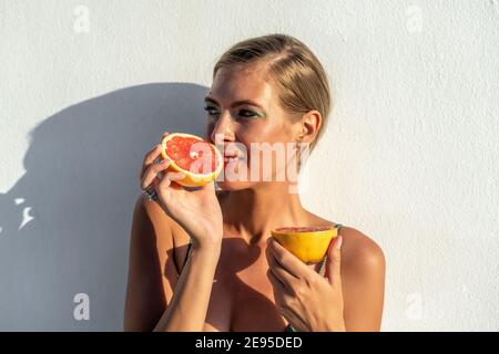 Belle jeune femme en maillot de bain avec un pamplemousse. Mode été concept. Banque D'Images