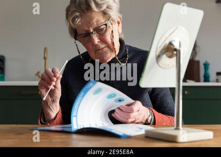 Une femme lit les instructions pour un coronavirus à la maison test par écouvillon Banque D'Images