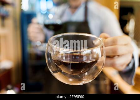 Double verre tasse en gros plan avec café dans le café. Le barista vous donne une tasse de café. Préparation alternative du café à l'aide de l'appareil Syphon. Banque D'Images