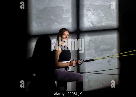 Une femme instructeur de fitness s'entraîner avec un élastique dans la salle de gym. Sport en ligne Banque D'Images