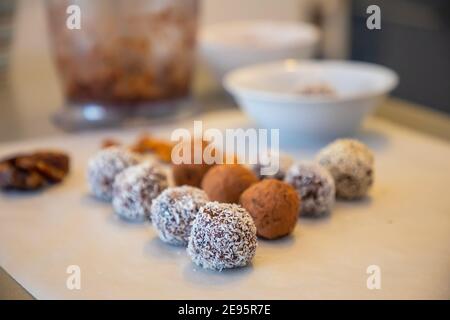 Boules de neige à la noix de coco faites à la main à partir de dattes, truffes aux amandes et à la noix de coco sur une surface grise Banque D'Images