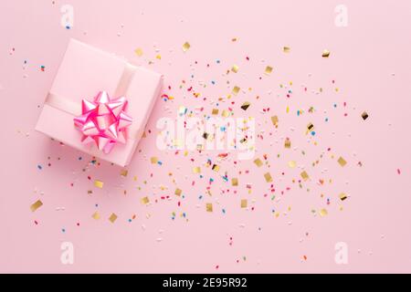Boîte cadeau avec confetti sur fond rose. Concept de fête minimal. Banque D'Images