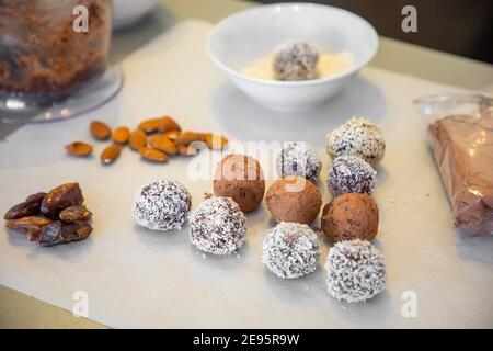 Boules de neige à la noix de coco faites à la main à partir de dattes, truffes aux amandes et à la noix de coco sur une surface grise Banque D'Images