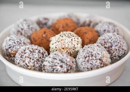 Boules de neige à la noix de coco faites à la main à partir de dattes, truffes aux amandes et à la noix de coco sur une surface grise Banque D'Images