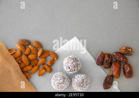 Boules de neige à la noix de coco faites à la main à partir de dattes, truffes aux amandes et à la noix de coco sur une surface grise Banque D'Images