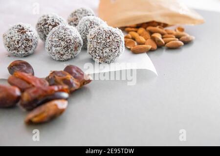 Boules de neige à la noix de coco faites à la main à partir de dattes, truffes aux amandes et à la noix de coco sur une surface grise Banque D'Images