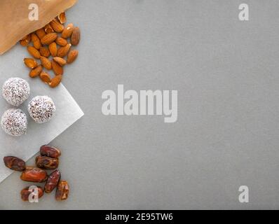 Boules de neige à la noix de coco faites à la main à partir de dattes, truffes aux amandes et à la noix de coco sur une surface grise Banque D'Images