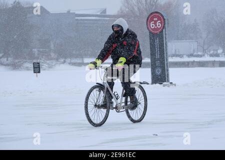 Ottawa, Canada. 2 février 2021. Cycliste utilisant la glace de la patinoire du canal Rideau pour se déplacer dans la capitale canadienne Banque D'Images