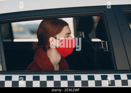 Une jeune femme passager prend un trajet en voiture de taxi pendant la quarantaine pandémique du coronavirus. Femme portant un masque médical stérile. Concept de la distance sociale et de la sécurité sanitaire dans les transports Banque D'Images