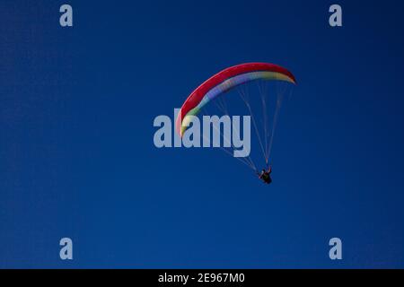 Parachute parapente bleu et rouge sur ciel bleu clair avec espace copie. Parapente contre ciel bleu Banque D'Images