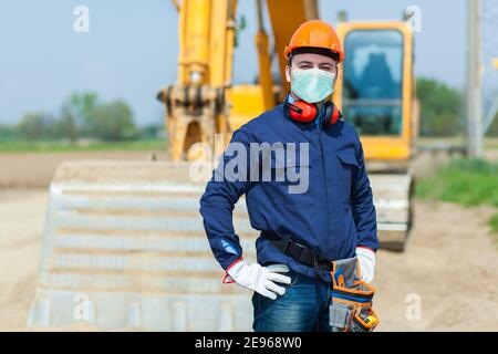 Portrait d'un travailleur masqué dans un chantier de construction, concept de coronavirus covid Banque D'Images