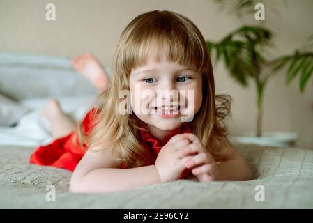 portrait de bébé heureux.emotive bébé fille sur le lit dans une chambre lumineuse. chambre blanche confortable, enfant gai. hurle émotionnellement, rires et réjouissances Banque D'Images