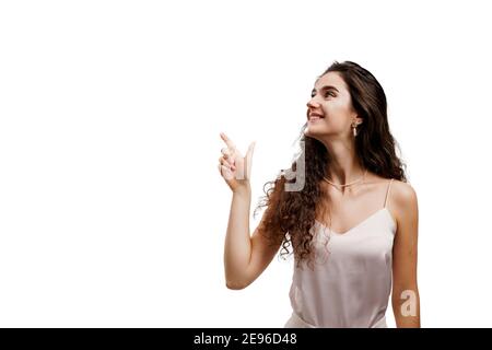 Une jeune femme attirante se dirige vers le haut et sourit sur fond blanc. Fille pointe vers le haut et donne 2 variantes à choisir. Promotion de la publicité en vente Banque D'Images