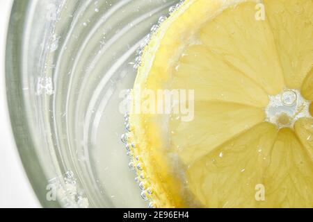 Détail de verre avec eau et tranche de citron flottant. Vue de dessus. Composition horizontale. Banque D'Images