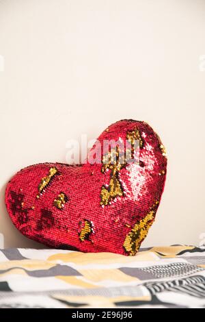 Coussin coeur rouge et doré sur un lit dans un chambre blanche Banque D'Images