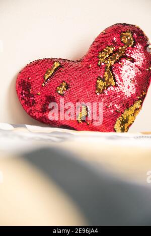 Coussin coeur rouge et doré sur un lit dans un chambre blanche Banque D'Images