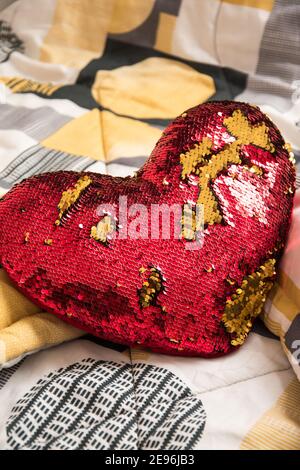 Coussin coeur rouge et doré sur un lit dans un chambre blanche Banque D'Images