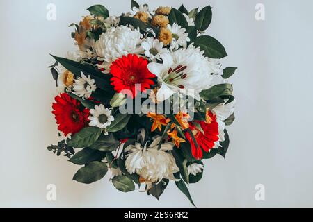 Bouquet lumineux de gerberas, chrysanthèmes, nénuphars, feuilles vertes sur fond clair. Carte de vœux avec fond floral pour toutes les occasions. Vue de dessus. Banque D'Images