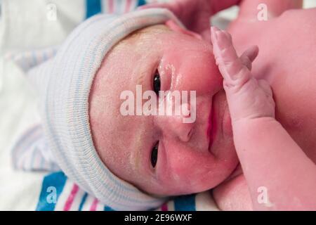 Visage avec les yeux ouverts de la jeune fille de nouveau-né dans une salle d'accouchement d'hôpital. Banque D'Images
