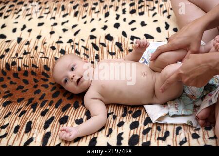 Mère faisant de la gymnastique pour bébé sur un lit Banque D'Images