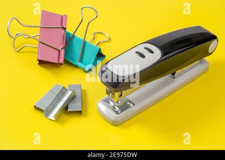 fournitures de bureau - agrafeuse, trombones et épingles à linge sur fond jaune Banque D'Images