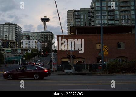 Seattle, WA-11.28.2018: L'aiguille spatiale de Seattle pointe derrière le grand immeuble d'appartements. À droite, une voiture se trouve derrière la vieille usine de spaghetti. Banque D'Images