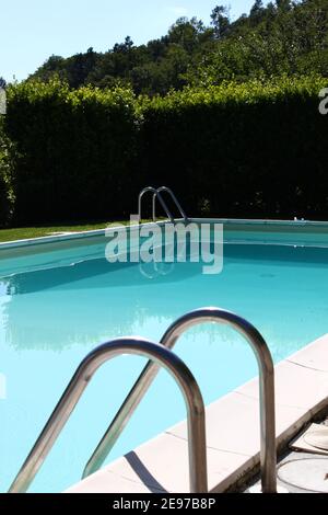 Le sondage de natation et les deux échelles entourées d'arbres par une journée ensoleillée pendant les vacances en Toscane. Banque D'Images