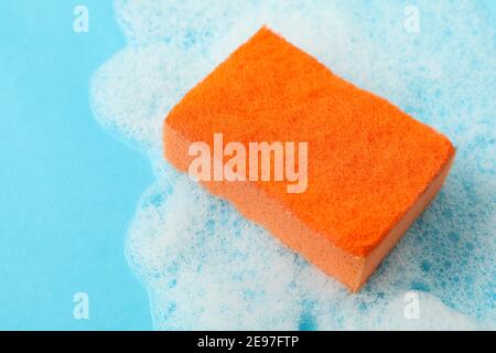 Éponge orange et mousse sur fond bleu Banque D'Images