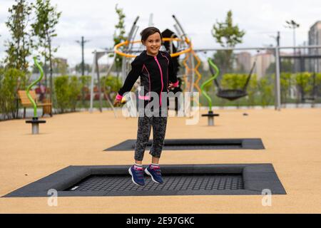 Une petite fille joue sur un terrain de sport de trampoline Banque D'Images