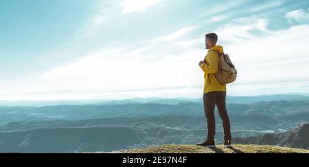 Jeune homme avec sac à dos debout sur le dessus d'un montagne au coucher du soleil - objectifs et réalisations Banque D'Images