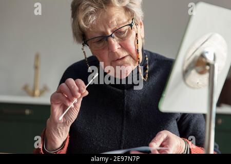 Une femme lit les instructions pour un coronavirus à la maison test par écouvillon Banque D'Images