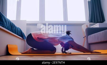Jeune femme africaine s'exerçant sur le tapis de yoga dans sa chambre. Photo de haute qualité Banque D'Images