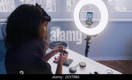 Jeune femme avec enregistrement de cheveux noirs maquillage tutoriel. Application du maquillage devant l'appareil photo. Photo de haute qualité Banque D'Images