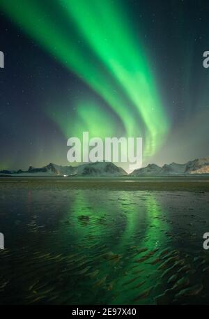 Aurores boréales au-dessus des montagnes sur les îles Lofoten. Réflexions de l'Aurora Borealis sur la plage de sable de Sandbotten. Belles conditions hivernales dans la mort Banque D'Images