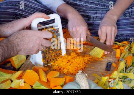 Faire la pâtisserie douce à la citrouille. Femme coupant et trancheuse une citrouille sur la planche à découper tout en étant assise sur le sol dans la cuisine à la maison. À râper Banque D'Images