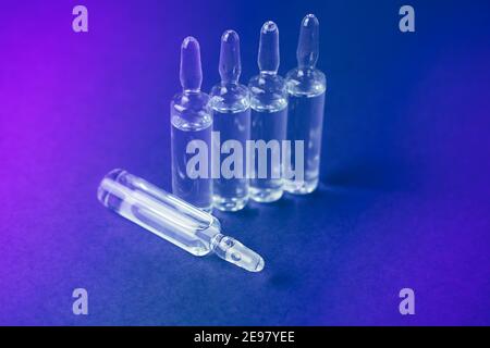 Ampoules en verre avec liquide sur fond néon. Banque D'Images