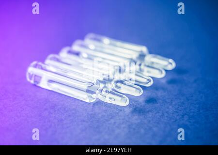 Ampoules en verre avec liquide sur fond néon. Banque D'Images