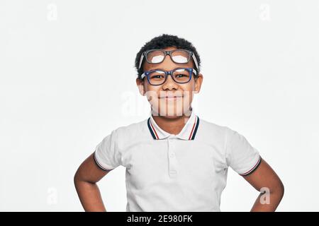 Afro-américain garçon avec des émotions positives portant beaucoup de lunettes stylées sur fond blanc. Enfants, correction de la vision Banque D'Images