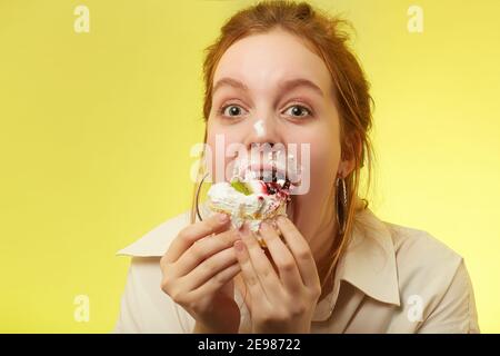 sympa jolie fille de cheveux rouges avec le syndrome de duvet mange doux dessert sur fond jaune Banque D'Images