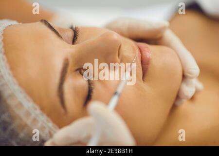 Les mains du cosmétologue faisant une injection de beauté dans les lèvres des womans Banque D'Images