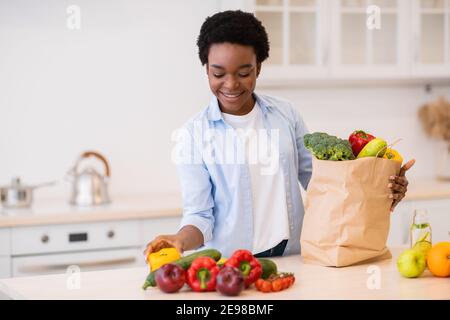 Bonne Black Lady Déballage après l'épicerie Shopping dans la cuisine à l'intérieur Banque D'Images