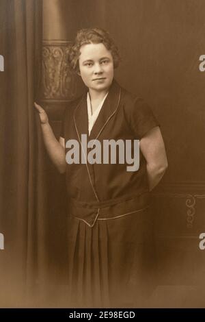 Allemagne - VERS les années 1930 : portrait d'une jeune femme debout en studio, photo Vintage carte de vue Art déco Banque D'Images